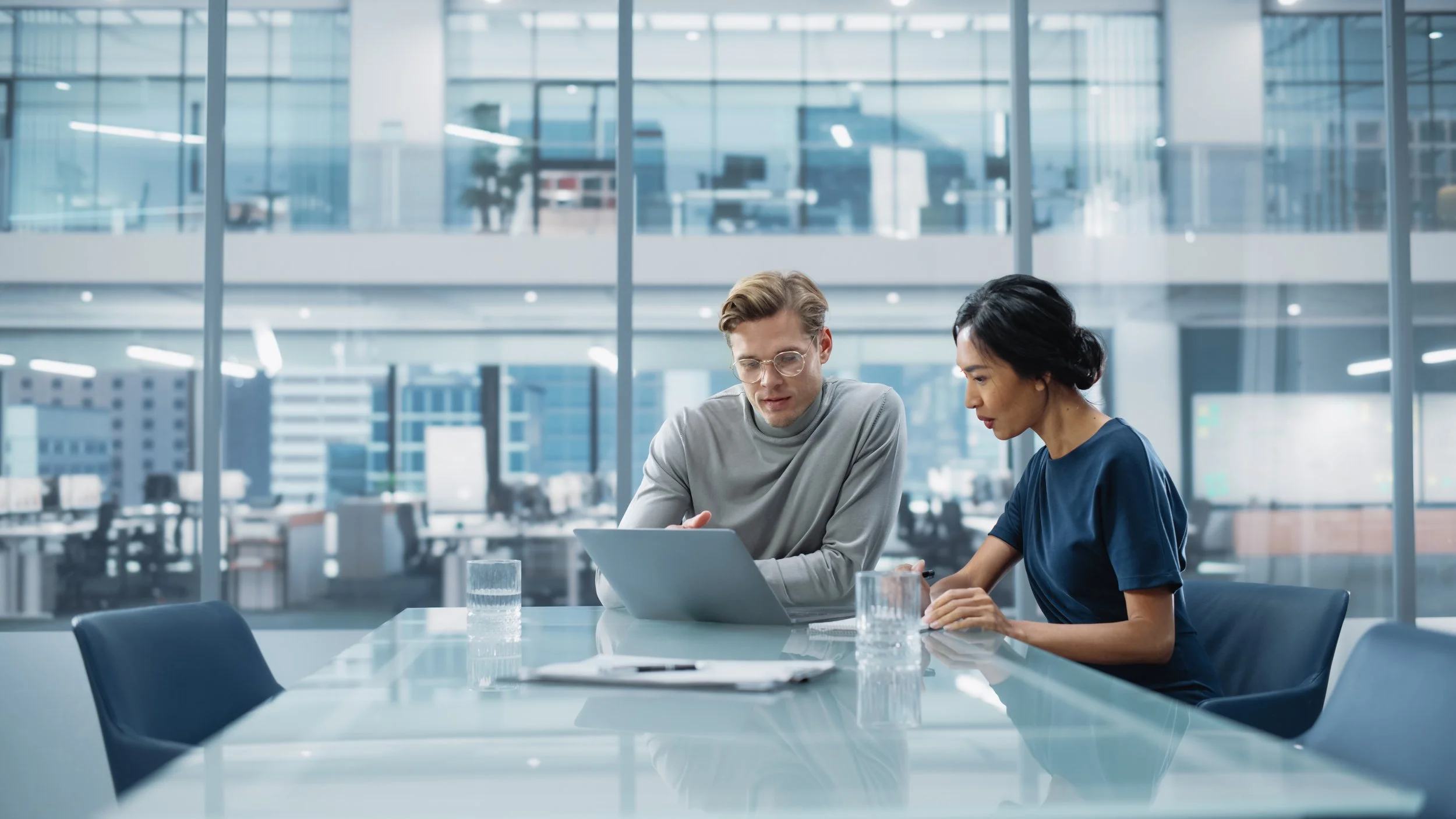 Two colleagues reviewing a compliance case together on a laptop in a modern office